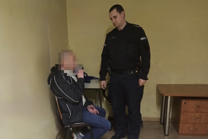na zdjęciu policjant stoi przy mężczyźnie w trakcie badania alkomatem