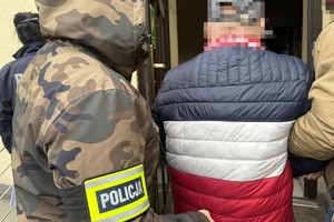 na zdjęciu policjanci prowadzą zatrzymanego