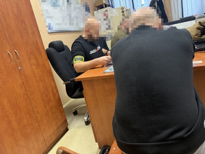 na zdjęciu policjant przy biurku z zatrzymanym