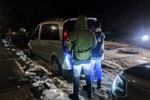 na zdjęciu policjant po cywilu z zatrzymanym przy samochodzie