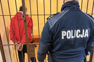 na zdjęciu policjant przed celą, w którym stoi zatrzymany mężczyzna