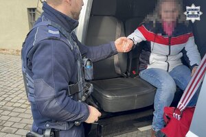 na zdjęciu policjant podaje dłoń kobiecie w trakcie wysiadania z radiowozu