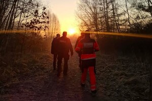 na zdjęciu policjanci i ratownicy o wschodzie słońca w terenie