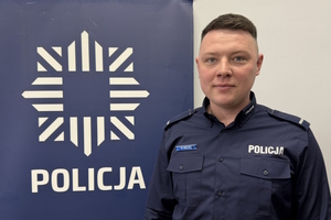 na zdjęciu dzielnicowy przy banerze z napisem policja