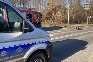 na zdjęciu radiowóz i wóz strażacki a pomiędzy nimi na jezdni przewrócony motocykl