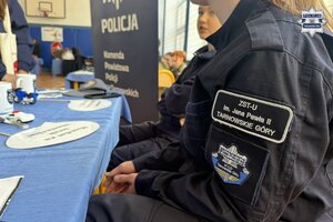 na zdjęciu stoisko policyjne, przy którym stoją osoby, policjant i uczennice w mundurach