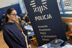 na zdjęciu stoisko policyjne, przy którym stoją osoby, policjant i uczennice w mundurach