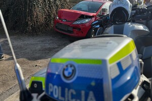 na zdjęciu fragment policyjnego motocykla i uszkodzony obok niego samochód osobowy