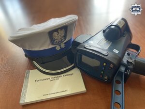 na zdjęciu policyjna czapka, bloczek mandatowy i miernik prędkości