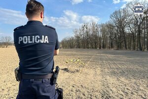 na zdjęciu policjant na polu w trakcie nadzoru nad niebezpiecznym znaleziskiem