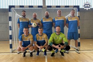 na zdjęciu policjanci w strojach sportowych w bramce na hali sportowej