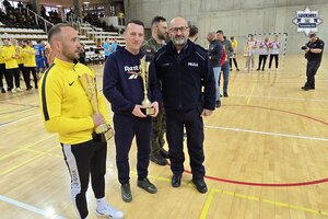 na zdjęciu policjant i inne osoby w hali sportowej