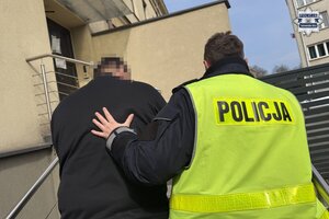 na zdjęciu policjant prowadzący zatrzymanego do budynku komendy