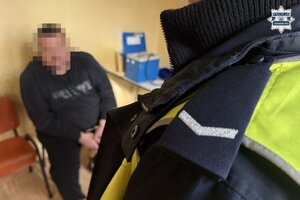 na zdjęciu fragment munduru policjanta, a przed nim zatrzymany siedzący na krześle