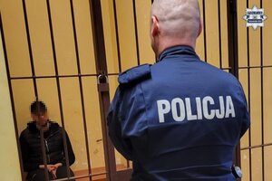 na zdjęciu policjant przed celą, w której siedzi mężczyzna