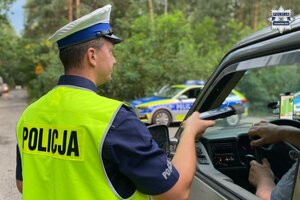 na zdjęciu policjant z alkomatem przy samochodzie