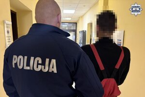na zdjęciu policjant z osobą obok w korytarzu