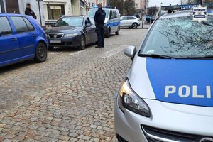 na zdjęciu droga, na której widać samochody, radiowóz, policjantów i osoby