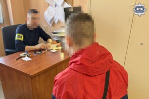 na zdjęciu zatrzymany mężczyzna przy biurku, za którym siedzi policjant