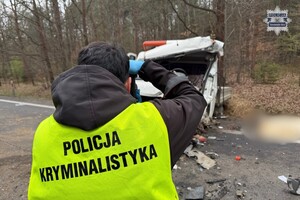 na zdjęciu policjant w odblaskowej kamizelce z napisem policja kryminalistyka w trakcie wykonywania zdjęć przed samochodem na jezdni