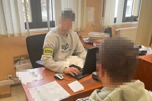 na zdjęciu zatrzymany przed biurkiem, za którym siedzi policjant z opaską z napisem policja na ramieniu