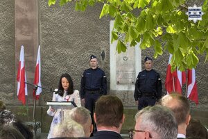 na zdjęciu przy mównicy kobieta, za nią policjanci w trakcie warty honorowej