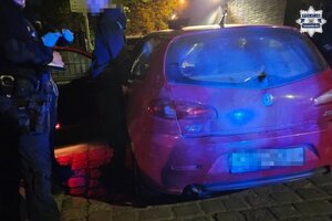 na zdjęciu samochód, przy którym stoi zatrzymany z policjantami