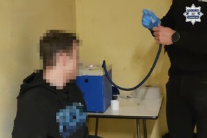 na zdjęciu zatrzymany przy policjancie w trakcie badania alkomatem