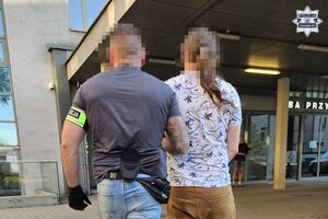 na zdjęciu policjant po cywilu prowadzący zatrzymanego