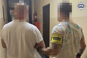 na zdjęciu policjant z zatrzymanym mężczyzną w korytarzu