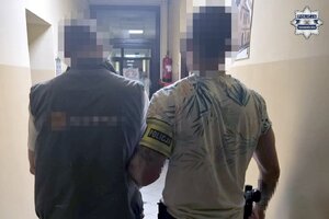 na zdjęciu policjant z zatrzymanym mężczyzną w korytarzu