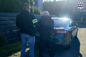 na zdjęciu policjant z zatrzymanym przy samochodzie