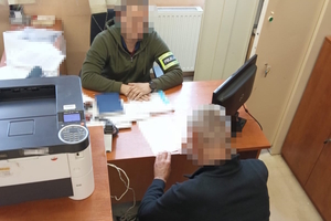 na zdjęciu mężczyzna przy biurku, za którym siedzi policjant