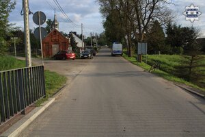 na zdjęciu samochód osobowy i radiowóz na drodze, obok osoby