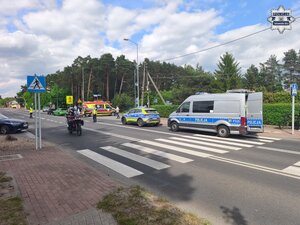 na zdjęciu policyjne radiowozy, samochody, karetka pogotowia i policjanci na skrzyżowaniu, gdzie na środku jezdni leży motocykl