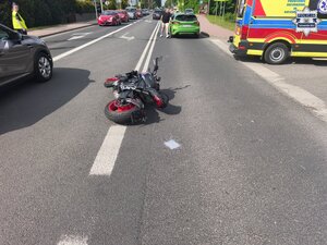 na zdjęciu policyjne radiowozy, samochody, karetka pogotowia i policjanci na skrzyżowaniu, gdzie na środku jezdni leży motocykl