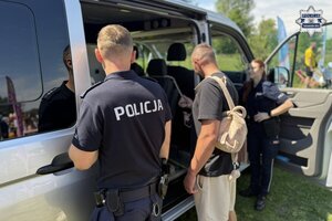na zdjęciu policjant z osobami przy nieoznakowanym radiowozie