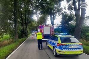 na zdjęciu radiowóz, obok policjant a przed nim wóz strażacki