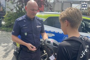 na zdjęciu policjant wręcza kask osobie