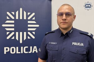 na zdjęciu dzielnicowy przy banerze z napisem policja