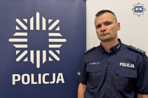 na zdjęciu dzielnicowy przy banerze z napisem policja