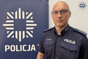 na zdjęciu dzielnicowy przy banerze z napisem policja