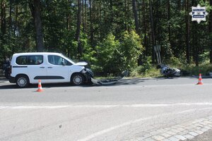 na zdjęciu leżący na jezdni motocykl i stojący z uszkodzeniami na jezdni pojazd