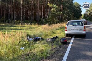 na zdjęciu samochód osobowy na jezdni, obok w rowie motocykl
