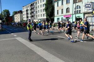 na zdjęciu policjant na jezdni obok biegacze