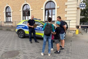 na zdjęciu policjant przy radiowozie z uczestnikami gry miejskiej