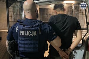 na zdjęciu policjant z zatrzymanym przed radiowozem