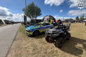 na zdjęciu quad, na którym siedzi policjant, obok radiowóz i teren imprezy