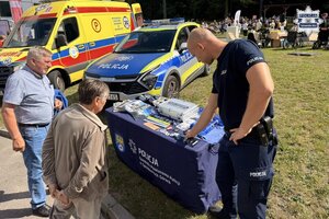 na zdjęciu policjant i osoby przy stoliku z gadżetami